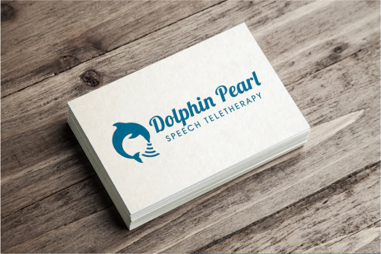 Business cards with a dolphin logo and the text "Dolphin Pearl Speech Teletherapy" on a wooden surface, shown in different color variations.